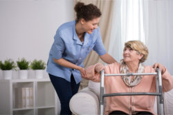 caregiver assisting the senior woman to stand